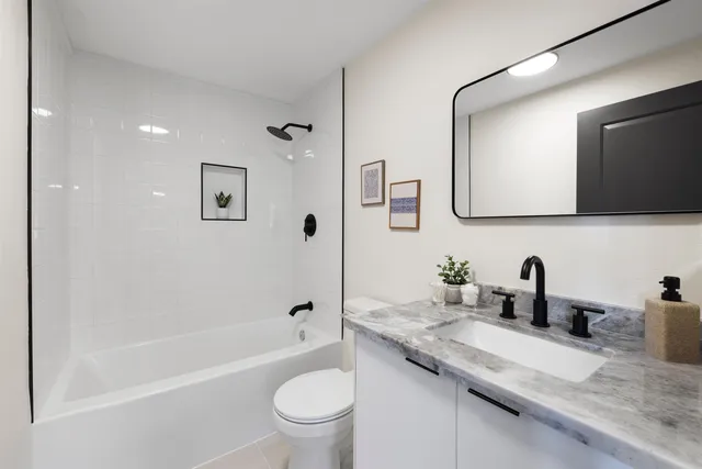 a bathroom with a granite countertop sink a toilet a mirror and shower