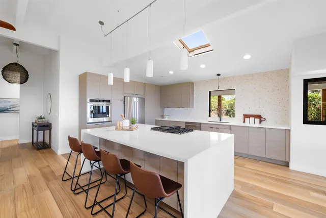 a kitchen with stainless steel appliances kitchen island a table chairs and wooden floor