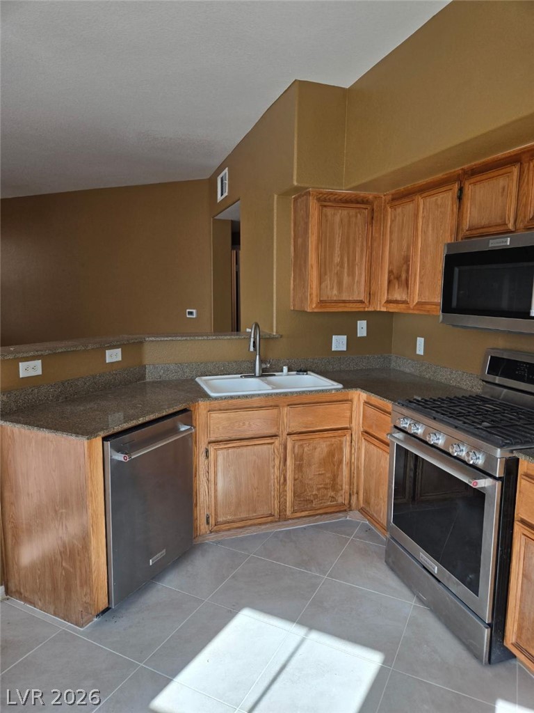 10550 West Alexander Road, Unit 1040 Las Vegas, NV 89129 - Photo 10 of 18 Classic wooden cabinetry pairs with stone countertops in this functional kitchen.