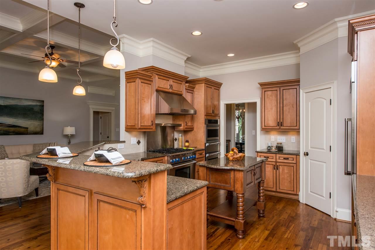 3003 Greyhawk Place Apex, NC 27539 - Photo 7 of 25 a kitchen with a refrigerator a stove a sink dishwasher a dining table and chairs with wooden floor