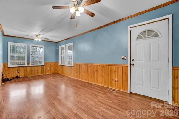 a view of empty room with wooden floor and fan