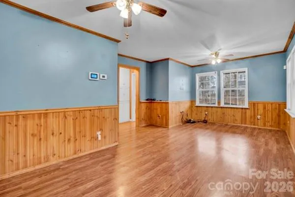 an empty room with wooden floor chandelier fan and windows