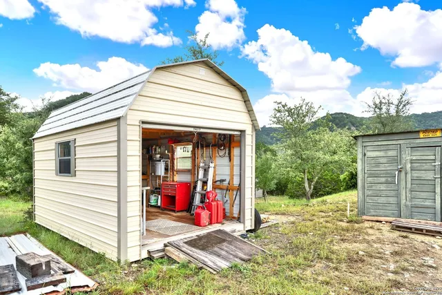 a view of a small house with floor to ceiling windows and a small yard