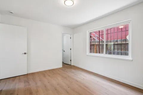 a view of an empty room with wooden floor and windows