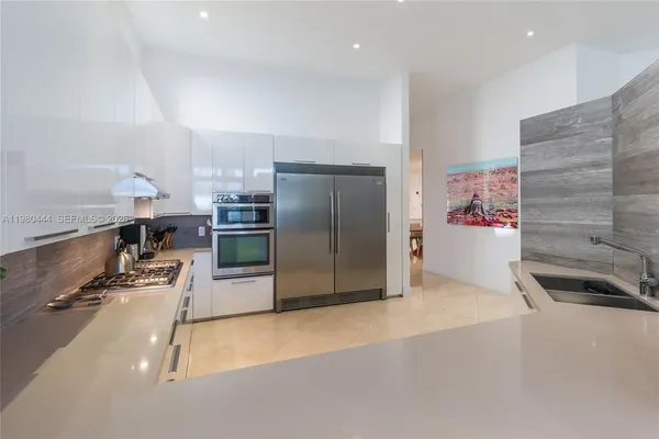 a large white kitchen with granite countertop a sink and a stove top oven