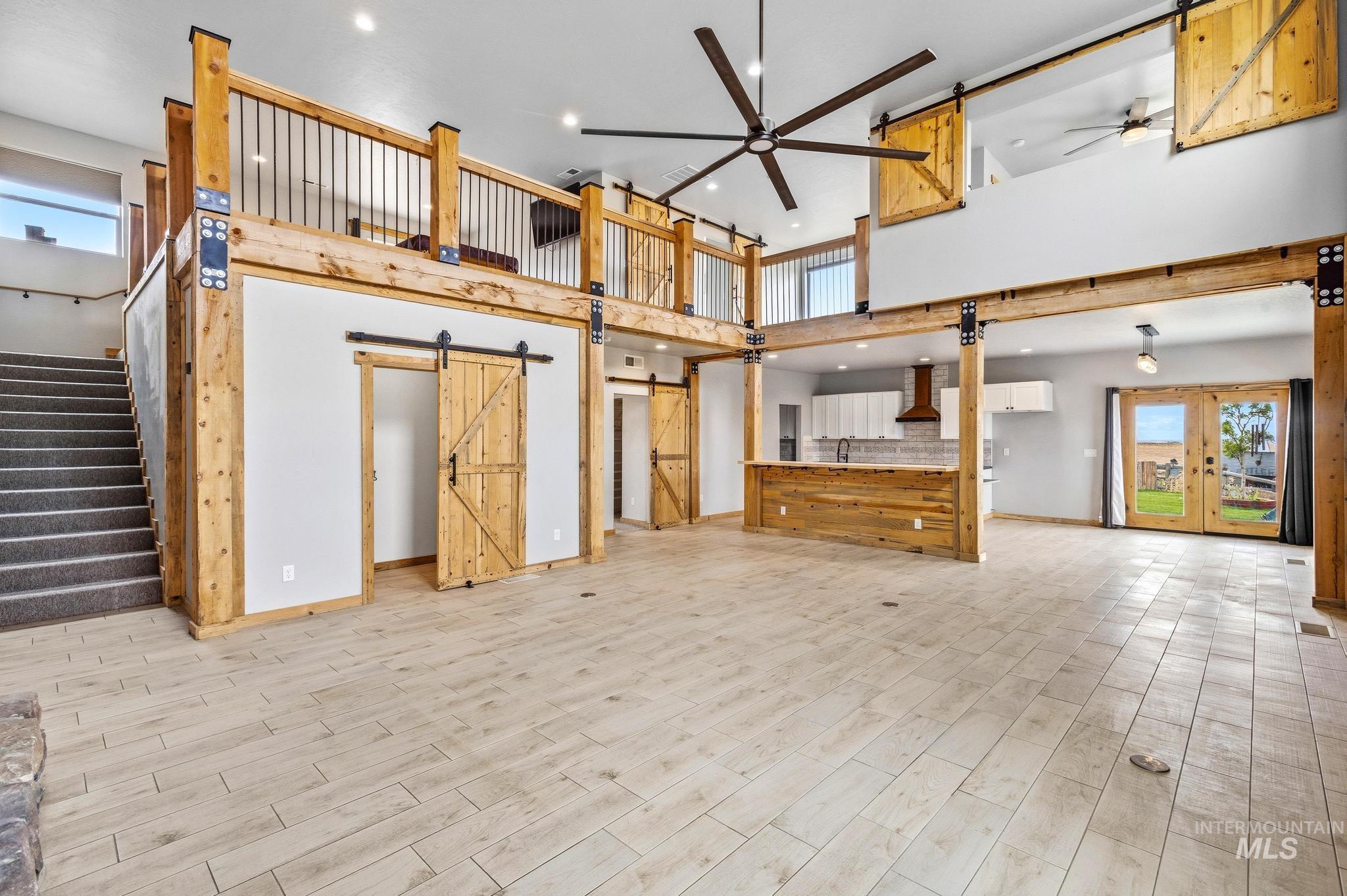 870 Desert Wind Road Boise, ID 83716 - Photo 13 of 50 Two-story living area featuring a stone fireplace with a wood mantle, a large ceiling fan, wood-finish flooring, and a second-story loft with wood railing