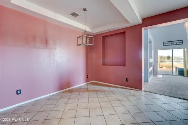 an empty room with chandelier fan and windows
