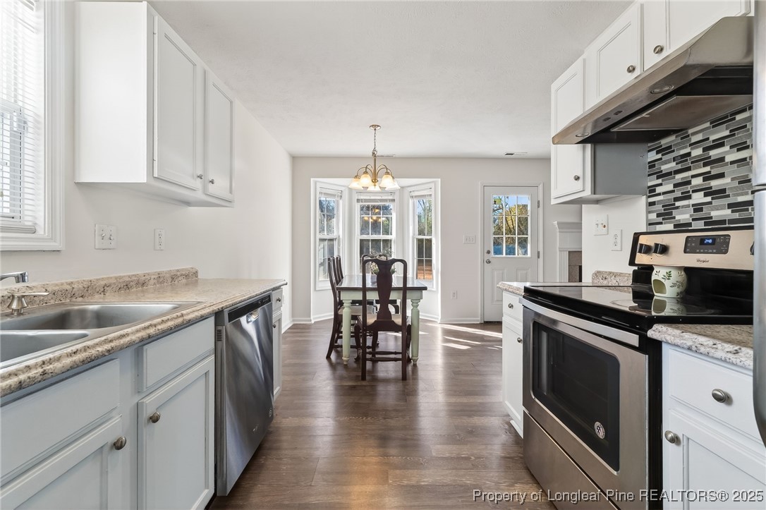 240 Rock Harbor Lane Spring Lake, NC 28390 - Photo 15 of 35 a kitchen with granite countertop a stove top oven a sink a dining table and chairs