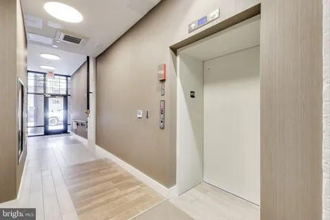 a view of a hallway with wooden floor and a bathroom