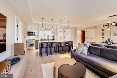 a living room with furniture kitchen view and a wooden floor