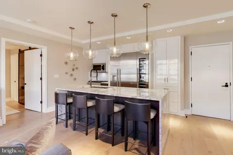 a kitchen with stainless steel appliances granite countertop a table chairs sink and cabinets