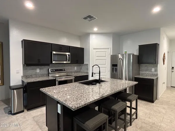 a kitchen with stainless steel appliances a stove a sink a microwave a refrigerator and cabinets