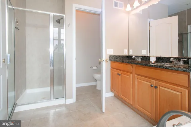 a spacious bathroom with a granite countertop sink a mirror and a bathtub