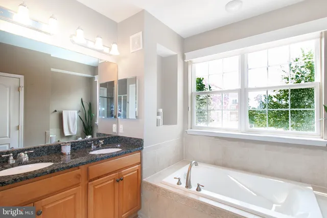 a bathroom with a granite countertop tub sink and mirror