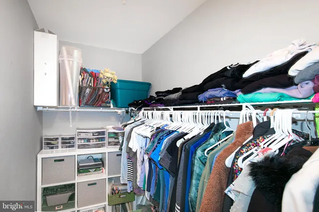 a view of walk in closet with clothes and shoes