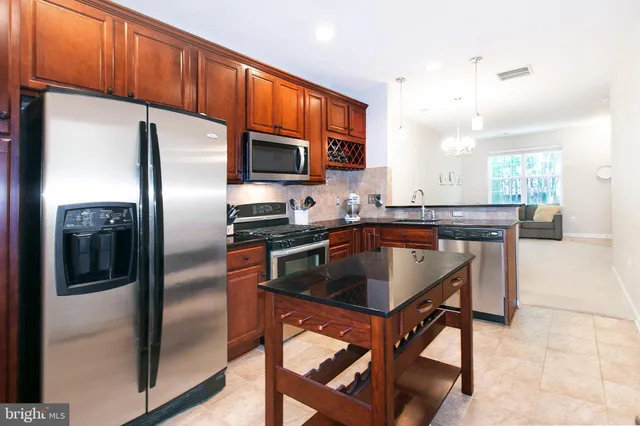 a kitchen with stainless steel appliances granite countertop a refrigerator a stove a sink and a microwave