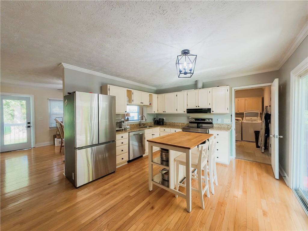 3905 Hunt Drive Gainesville, GA 30507 - Photo 7 of 16 a kitchen with granite countertop a refrigerator a stove a sink and a dining table with wooden floor