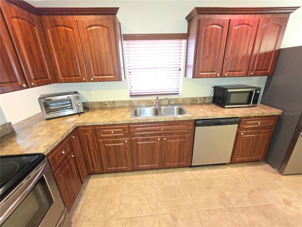 4284 High Ridge Avenue Spring Hill, FL 34609 - Photo 4 of 40 a kitchen with stainless steel appliances granite countertop a sink a stove a microwave oven and a refrigerator