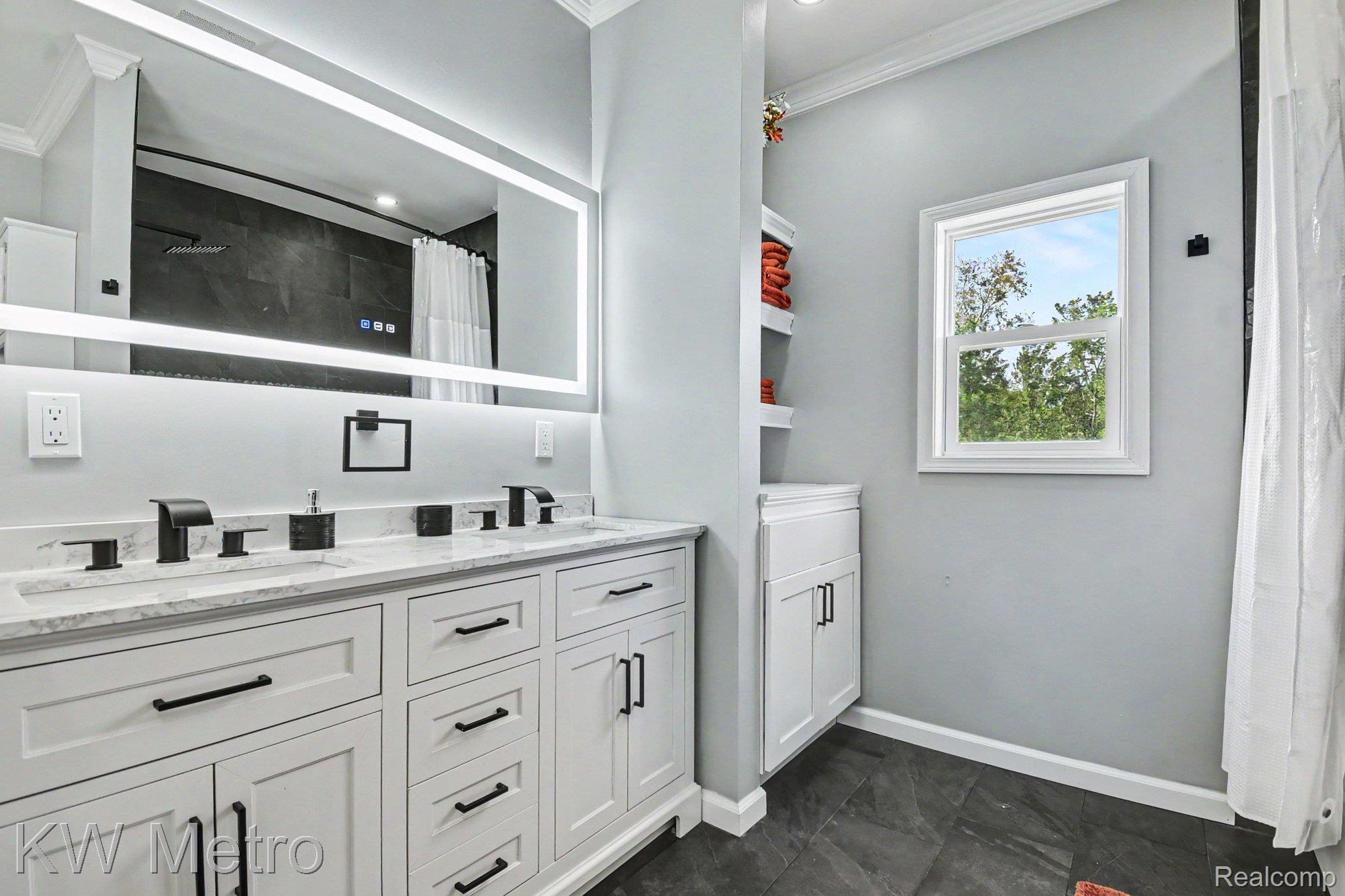 2682 East Haskell Lake Road Harrison, MI 48625 - Photo 21 of 61 Bathroom featuring a double vanity with white cabinetry, matte black hardware, and an illuminated mirror