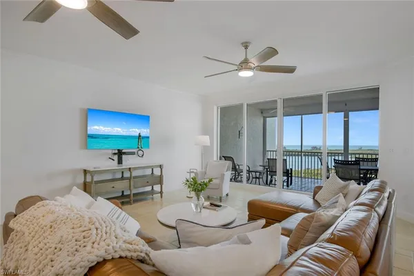 a living room with furniture ceiling fan and a floor to ceiling window