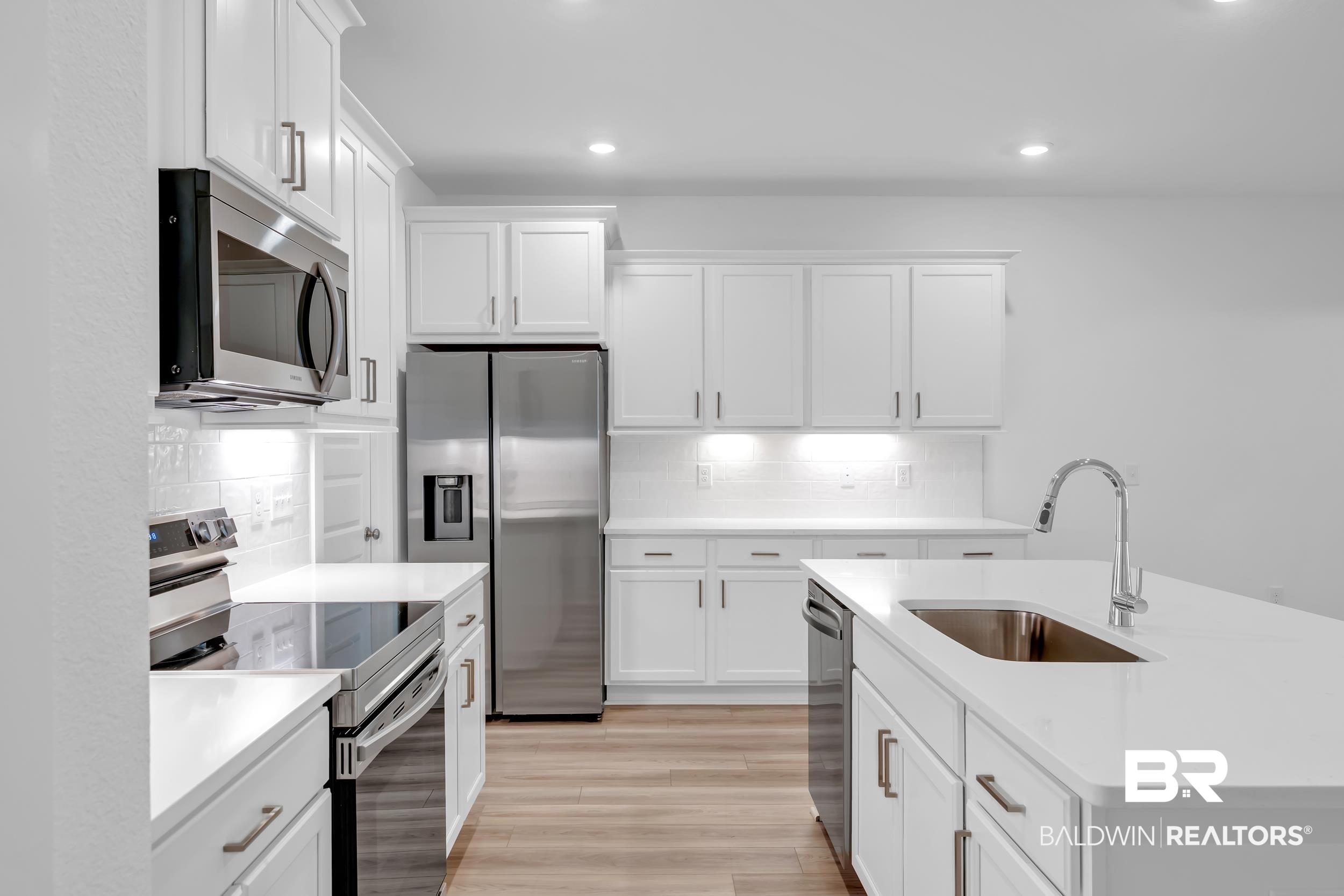 9933 Weller Cove Foley, AL 36535 - Photo 11 of 36 Modern kitchen featuring a large central island with an undermount sink and chrome faucet