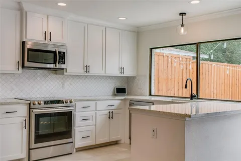 a kitchen with stainless steel appliances white cabinets and a stove top oven