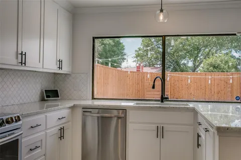 a kitchen with granite countertop white cabinets and a large window
