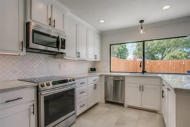 a kitchen with stainless steel appliances granite countertop white cabinets a microwave oven and a sink