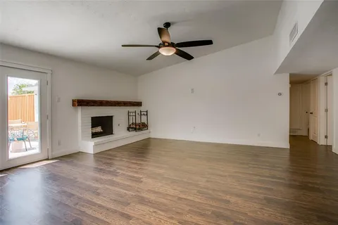 an empty room with wooden floor fireplace and windows
