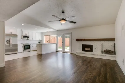 a view of an empty room with a kitchen and a fireplace