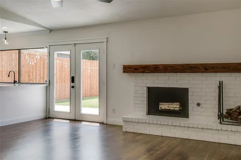 an empty room with wooden floor fireplace and windows