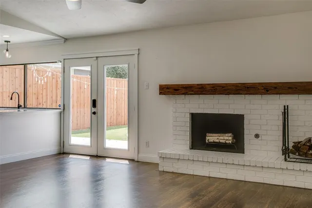 an empty room with wooden floor fireplace and windows