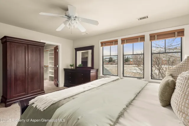 a bedroom with a large bed and a chandelier fan