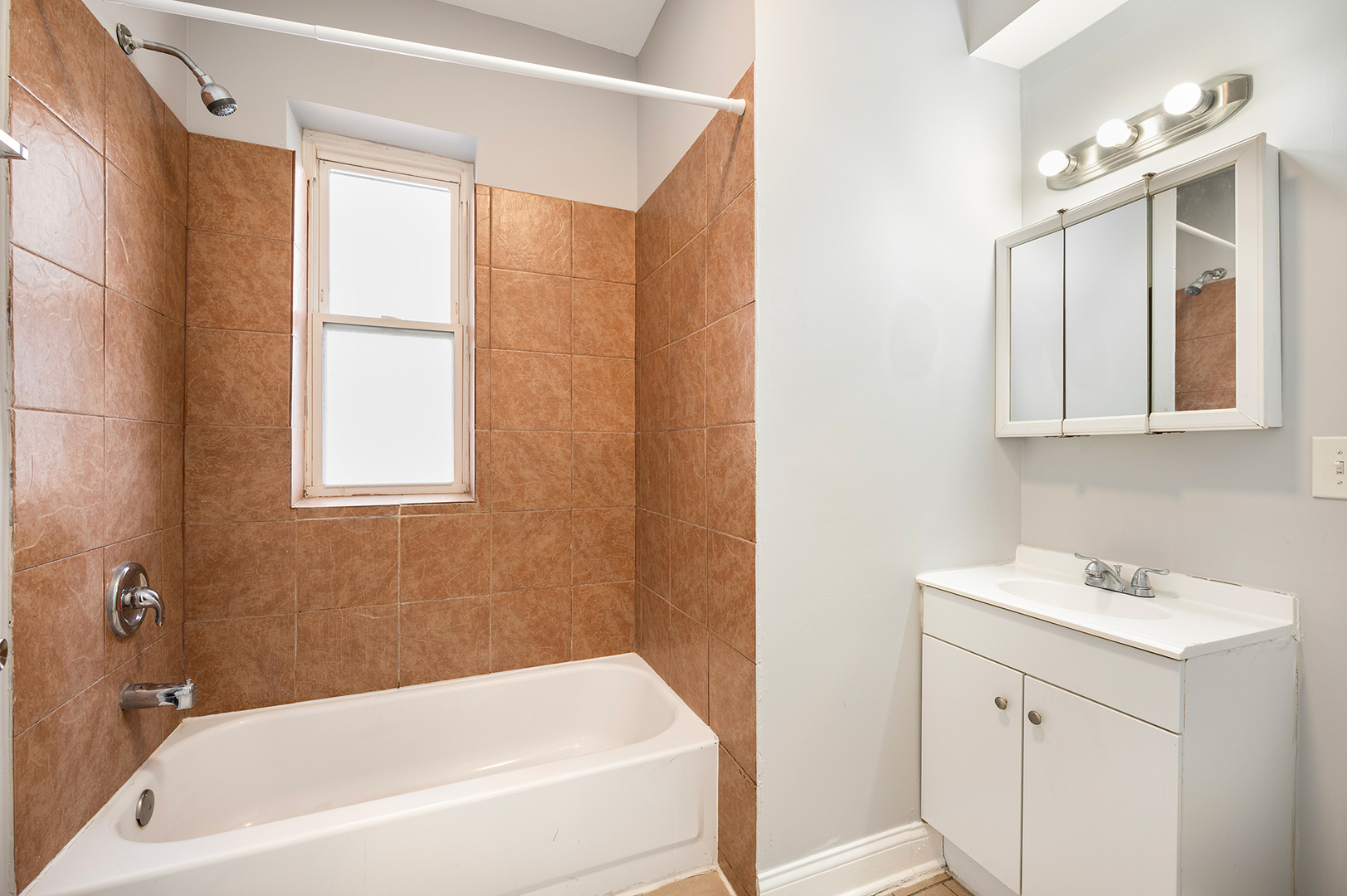 2437 East 74th Street, Unit 3W Chicago, IL 60649 - Photo 14 of 18 a bathroom with a bathtub a sink a vanity and a window