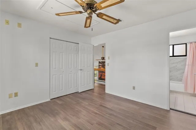 an empty room with wooden floor chandelier fan and closet area