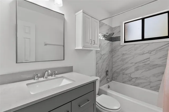a bathroom with a granite countertop sink toilet and bathtub