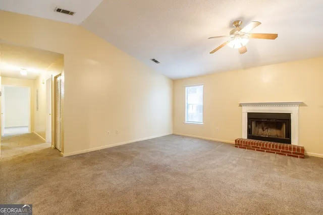 an empty room with chandelier fan and fireplace