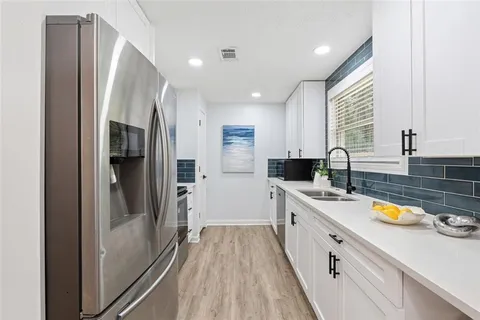 a large kitchen with a sink a refrigerator and a stove top oven