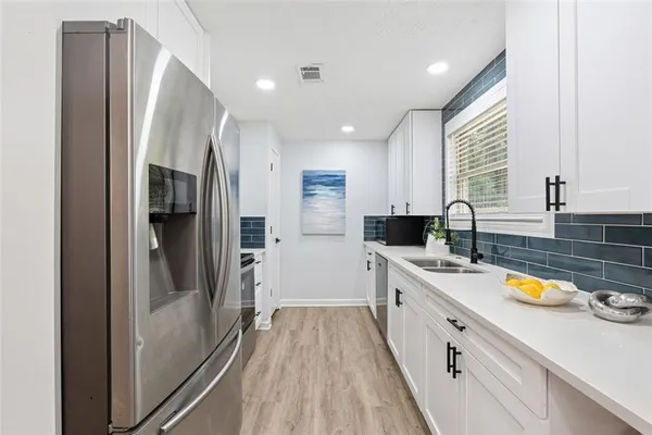 a large kitchen with a sink a refrigerator and a stove top oven