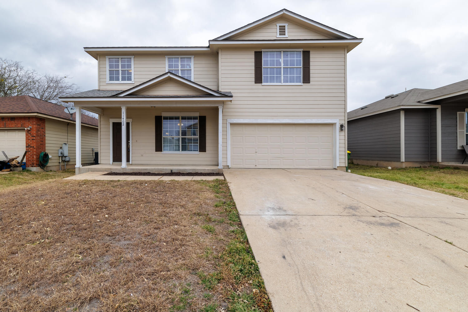 Traditional-style home featuring an attached garage, concrete driveway, and covered porch