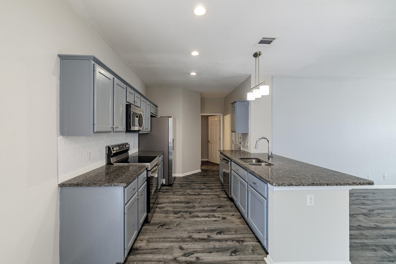 11402 Marshall Street Manor, TX 78653 - Photo 10 of 34 Kitchen featuring stainless steel appliances, dark stone countertops, gray cabinetry, and dark wood-type flooring