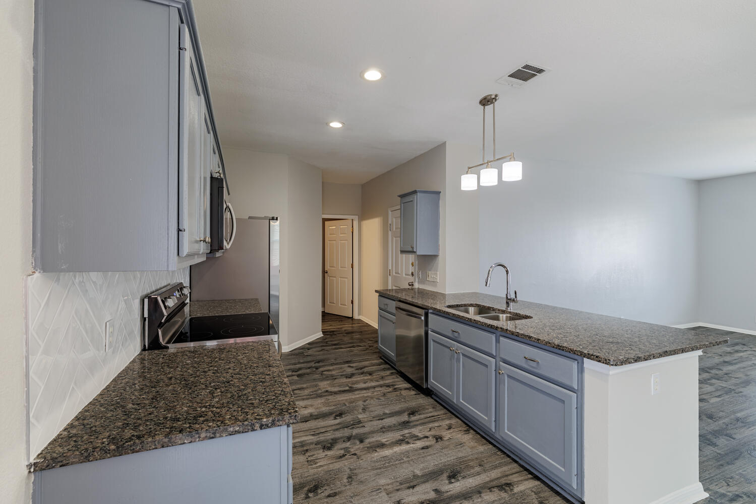 11402 Marshall Street Manor, TX 78653 - Photo 11 of 34 Kitchen featuring gray cabinets, dark stone counters, stainless steel appliances, dark wood-style floors, and hanging light fixtures