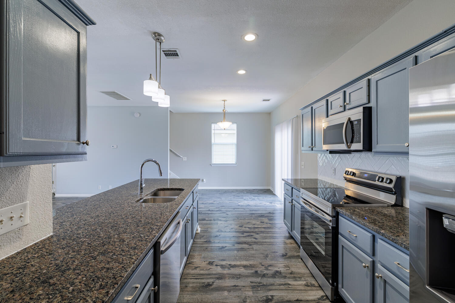 11402 Marshall Street Manor, TX 78653 - Photo 12 of 34 Kitchen featuring stainless steel appliances, dark wood finished floors, dark stone counters, pendant lighting, and gray cabinetry