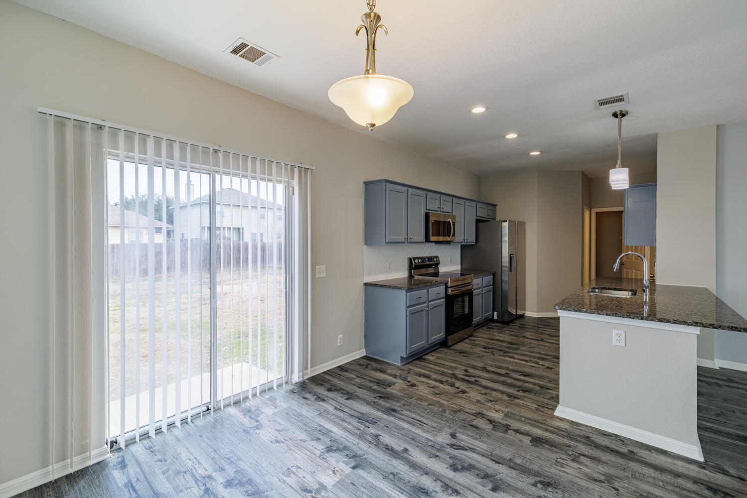 11402 Marshall Street Manor, TX 78653 - Photo 8 of 34 Kitchen featuring stainless steel appliances, dark stone countertops, gray cabinetry, pendant lighting, and dark wood finished floors