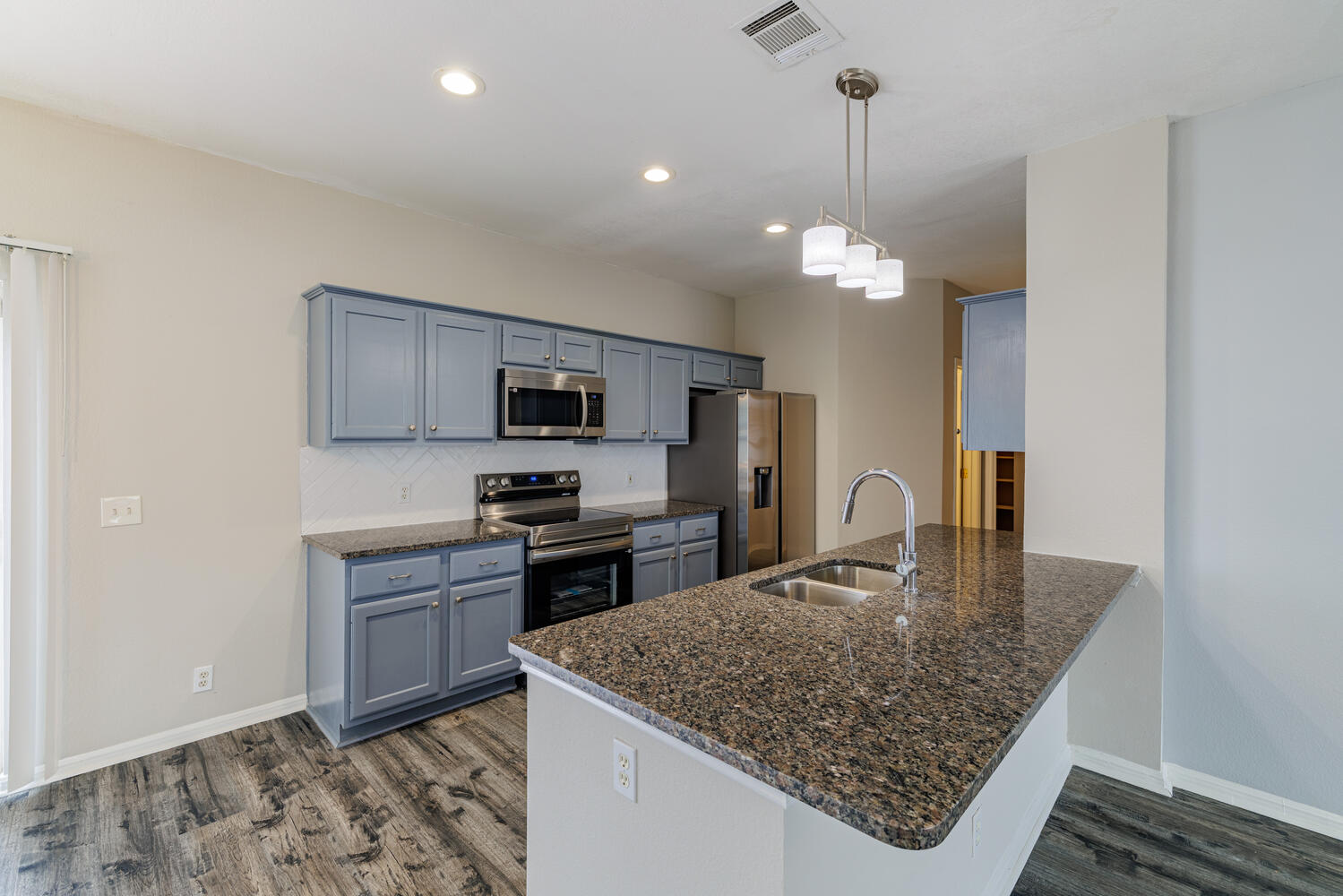 11402 Marshall Street Manor, TX 78653 - Photo 9 of 34 Kitchen featuring stainless steel appliances, dark wood-style floors, dark stone counters, and pendant lighting