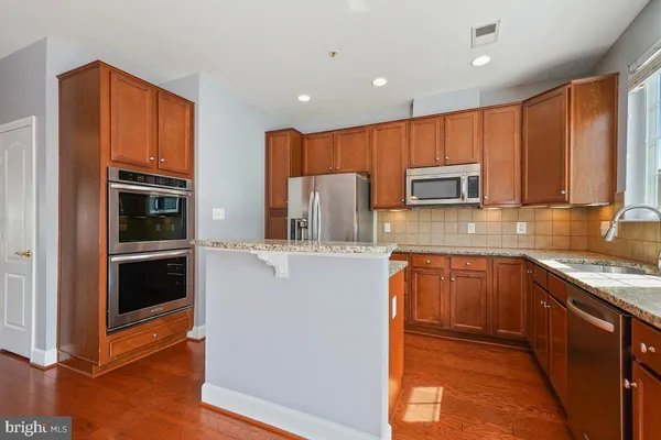 a kitchen with stainless steel appliances granite countertop a refrigerator microwave and sink