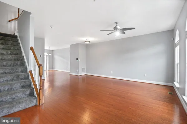 wooden floor in an empty room with a chandelier fan