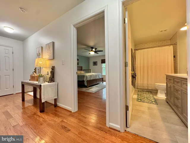 a spacious bedroom with a bed a dresser and wooden floor