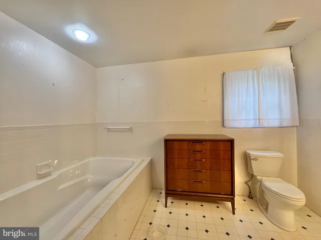 a spacious bathroom with a granite countertop sink a toilet and a mirror
