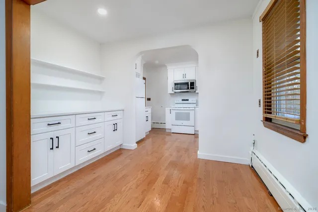 a room with white cabinets and wooden floor